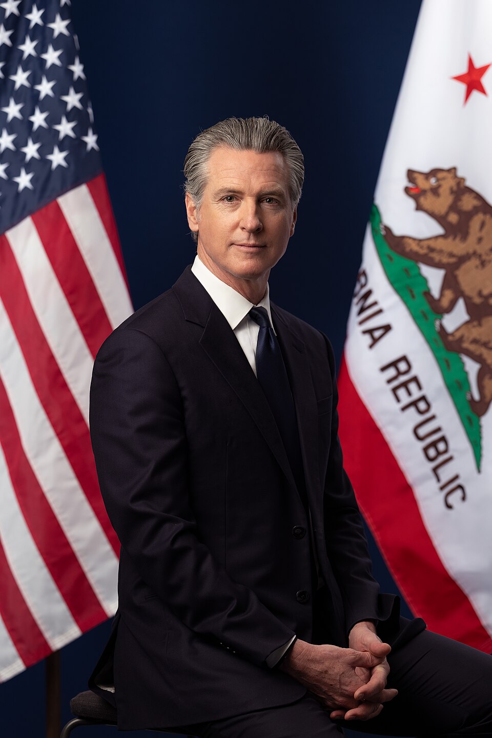 Retrato oficial de Gavin Newsom sentado entre las banderas de Estados Unidos y California. Imagen de archivo de marzo de 2026.